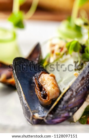 The concept of high European cuisine, molecular cuisine. Dish with sea products from mussels with vegetables. server table, on the table appliances and a glass of wine