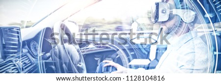 Digital composite of volume knob with graphs against man behind the wheel wearing a virtual reality helmet
