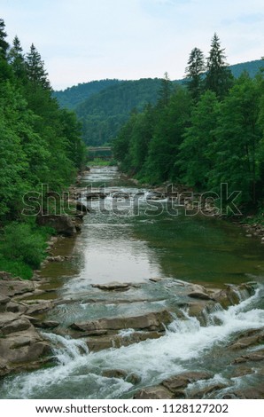stones and mountain river with small waterfall, blurred background
