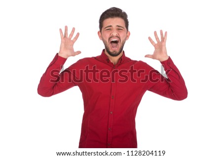 young angry man screaming while rising hands up , wearing red shirt, isolated on white background Royalty-Free Stock Photo #1128204119