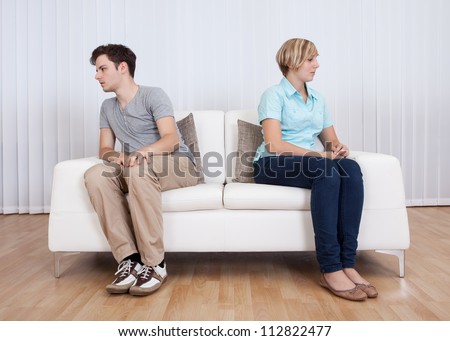 Brother and sister have had an argument and are sitting at opposite ends of a sofa Royalty-Free Stock Photo #112822477