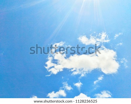 Sunlight shines in white clouds in bright blue sky.