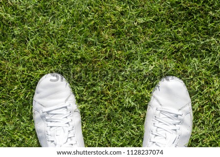 White used sneakers on a green grass.