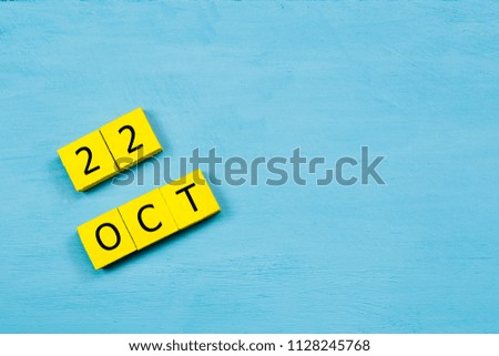 OCT 22, yellow cube calendar on blue wooden surface with copy space
