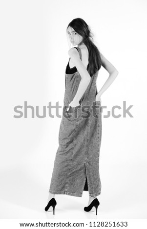 beauty and fashion. woman with long brunette hair in long fashionable jeans denim dress blue color and black shoes isolated on white background.