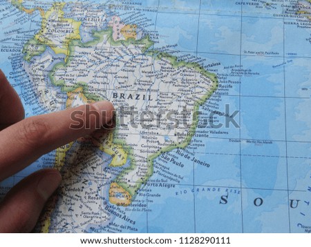 Person pointing at Brazil on a map for planning a vacation 