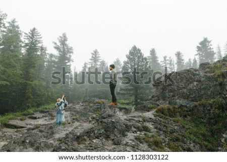 Young woman taking picture of her husband. Travelling together in the mountains