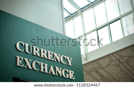 Closeup of currency exchange sign inside building with sunlight from the window glass roof   