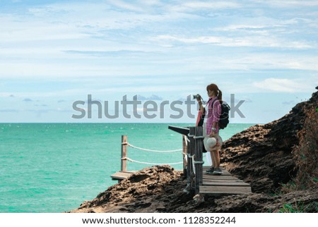 Woman tourist looking at the sea and picked up a camera to take pictures.(concept travel sea.)