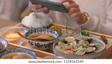 Woman taking photo on her dishes in Taiwanese restaurant 