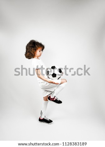 Soccer player juggling ball with his knee on a gray background