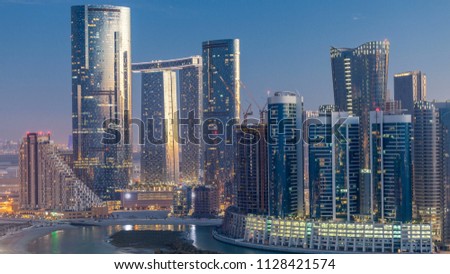Skyscrapers on Al Reem Island in Abu Dhabi day to night transition timelapse after sunset from above. Aerial citiscape from Al Reem Island with illuminated buildings