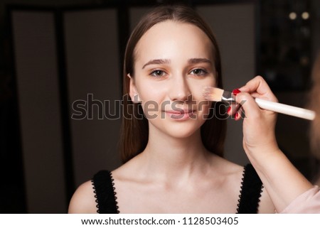 makeup artist applying the mixed foundation on a face of a young beautiful smiling model. concept of professional natural make up Royalty-Free Stock Photo #1128503405