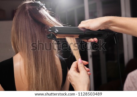 professional hairdresser making a gauffer hairstyle of a model with long hair in a beauty salon. concept of stylist training Royalty-Free Stock Photo #1128503489