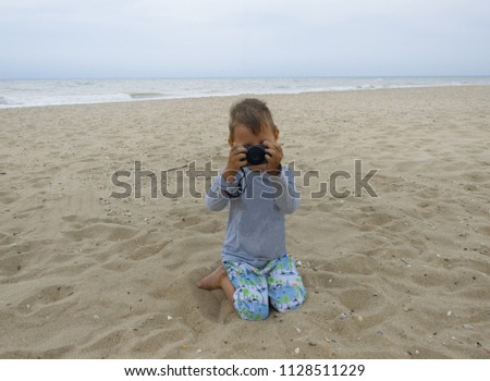 little boy taking pictures on the beach