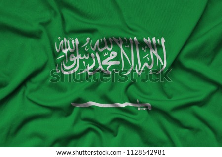 Saudi Arabia flag  is depicted on a sports cloth fabric with many folds. Sport team banner