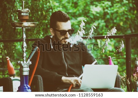 Man smoking hookah outside Royalty-Free Stock Photo #1128559163