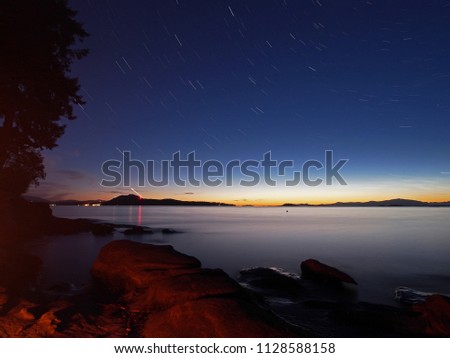 Star trails and sunset over water. The photo was taken in Nanaimo, British Columbia Canada, but it is suitable for a wide variety of uses.