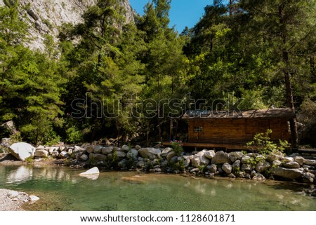 beautiful landscape with wooden house near the water with rocks and rock in the forest , on a hot Sunny day