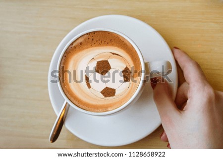 coffee cappuccino in a cup with a picture of a soccer ball made from cinnamon on milk foam