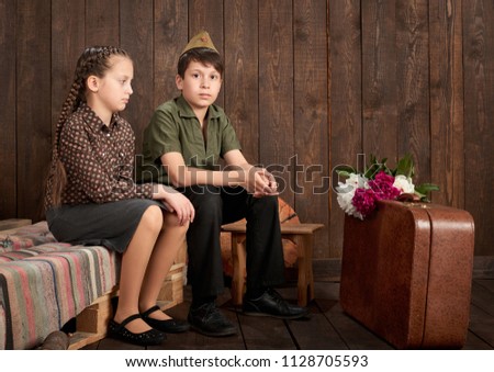 children are dressed in retro military uniforms sending a soldier to the army, dark wood background, retro style