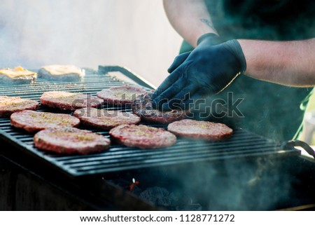 cook in black gloves prepares chops   for burger on the grill. Fast food