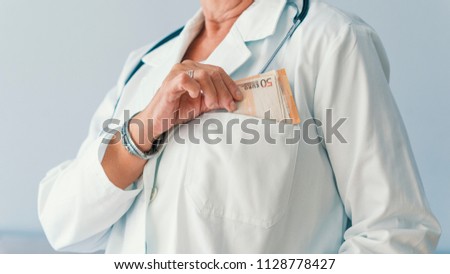 Doctor with bribe at workplace. Bribery in medicine. Wealthy female Doctor. Corruption in Health Care. Closeup on medical doctor with euros. Corrupt female doctor