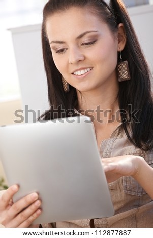 Young woman using tablet PC, smiling at home.