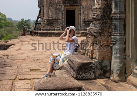 Tourist woman making pictures in Pre Rup temple, Angkor Wat complex, Cambodia. Tourist photographer in Angkor Wat. European tourist in ancient temple. Woman sightseeing cambodian place of interest