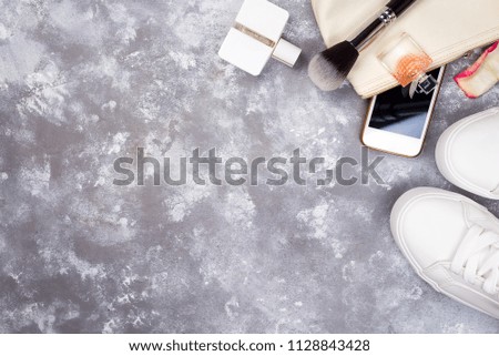 Still life of fashion woman. Women's fashion with petals of roses, cosmetics, phone and shoes on stone background, copy space