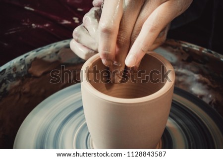 Creating ceramic products of white clay close-up. The sculptor in workshop makes clay jug closeup. Master crock. Twisted potter's wheel. Art creativity Cultural tradition Handmade Craft Master's Hands