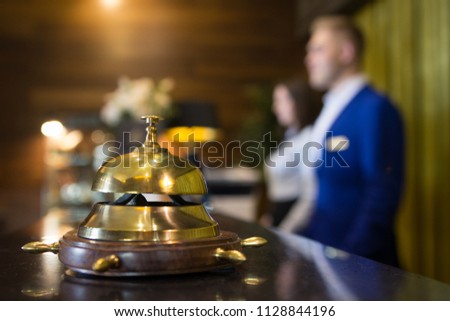 The golden reception bell is at the reception of a five-star hotel on the background of two administrators Royalty-Free Stock Photo #1128844196