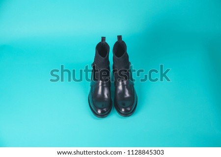 Black winter boots on a blue background. Autumn shoes on a colored background. Spring shoes with high heels on a turquoise background. Demi-season shoes