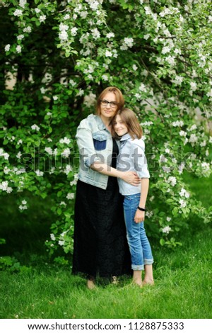 Beauty mother and her school aged daughter in theblooming garden