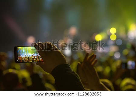 Fan holding smartphone and recording or taking picture during a  concert