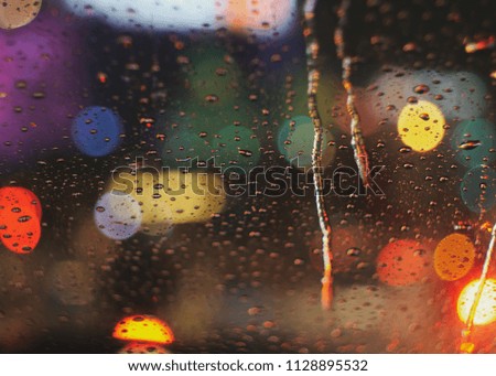 water drops on glass and bokeh lights on street , at night