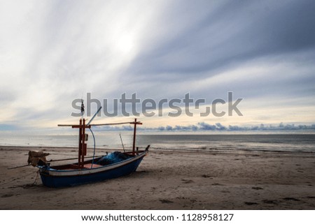 Old fishing boat made of wood anchored on the beach of the sea in the morning of Thailand