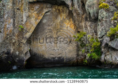 Travel New Zealand, North Island, Taupo. Cruise view of Iconic Maori rock carving in the rock on Great Lake Taupo. Popular tourist attraction/activity. Royalty-Free Stock Photo #1128960875