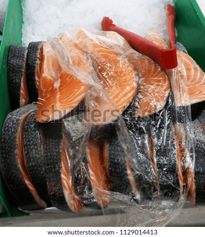 Salmon steaks on ice wrapped in cellophane in a green container
