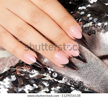 Hand with long artificial black french manicured nails 