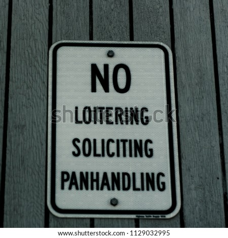 No loitering, soliciting, and panhandling text sign on white rectangle