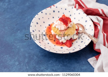 Homemade Strawberry Shortcake topped with Whipped Cream; Red and White Striped Towel; Blue Background