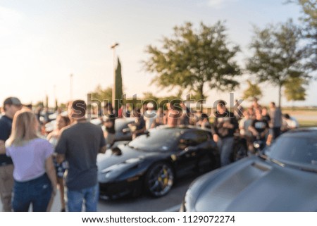 Abstract blurred diverse group of people attending local car show in Dallas, Texas, USA. Busy people browsing cars of all years, makes, models collection of luxury and super cars