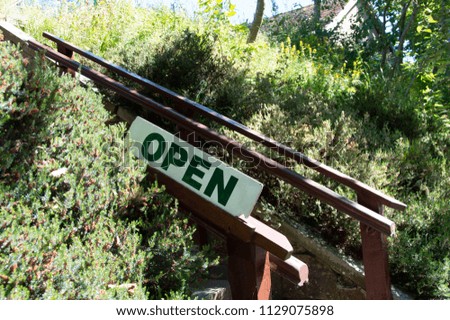 "Open" Sign Attached To Wooden Railings On Stairs Leading Up To Museum