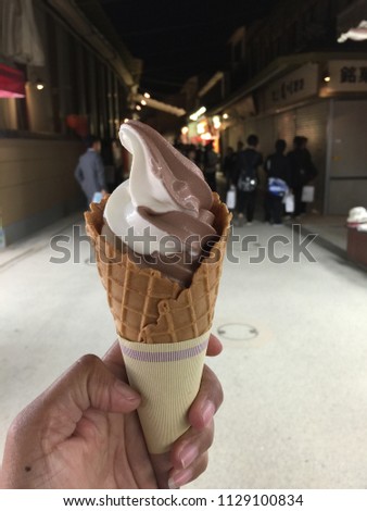 Girl hold Vanilla and chocolate two tone soft ice icecream in waffle cone at Miyajima Omotesando Shopping Street.