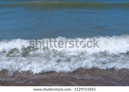 Waves crashing into the beach by the north sea in the Netherlands