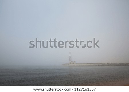 Lighthouse in the fog by the sea