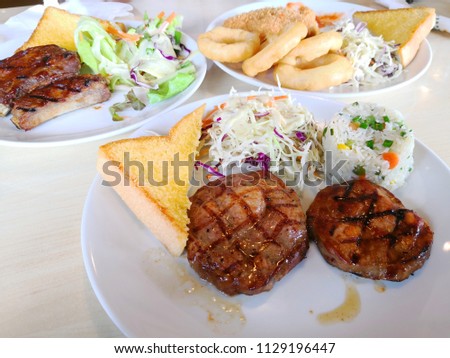 Close up Chicken ,pork , T-bone beef ,ribs steak served with french fries, soft drink ,Onion Rings and salads vegetables in cafe.Top view 