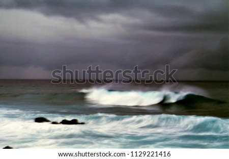 the sweet wave, shadow light contrast, photography at low shutter speed of a wave breaking on the beach with a storm in the background, to give an emotional impact,