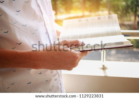 Education Learning Studying concept : Attractive Happy Asian Young man enjoy reading book for preparing final test exam at school building on vacation time in summer day.